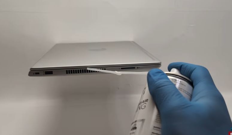 Dusting laptop air vents with a can of compressed air